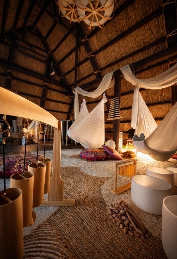 Inside a large thatched hut with white drapes and hammocks